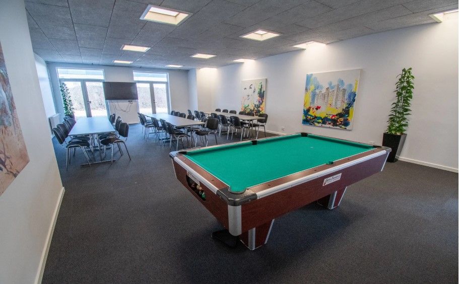 En stor poolborte i en moderne kontorlokaler med lyse lofter og malerier på væggen