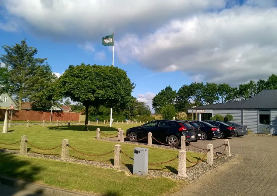 Sønderborg Golfklubs industribygning med parkeringsplads og flag og flere biler parkeret