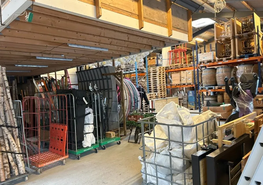 Lager med masser af ski, skistav, brædder, kasser og emballage. Plads med højt loft og lagerhylder