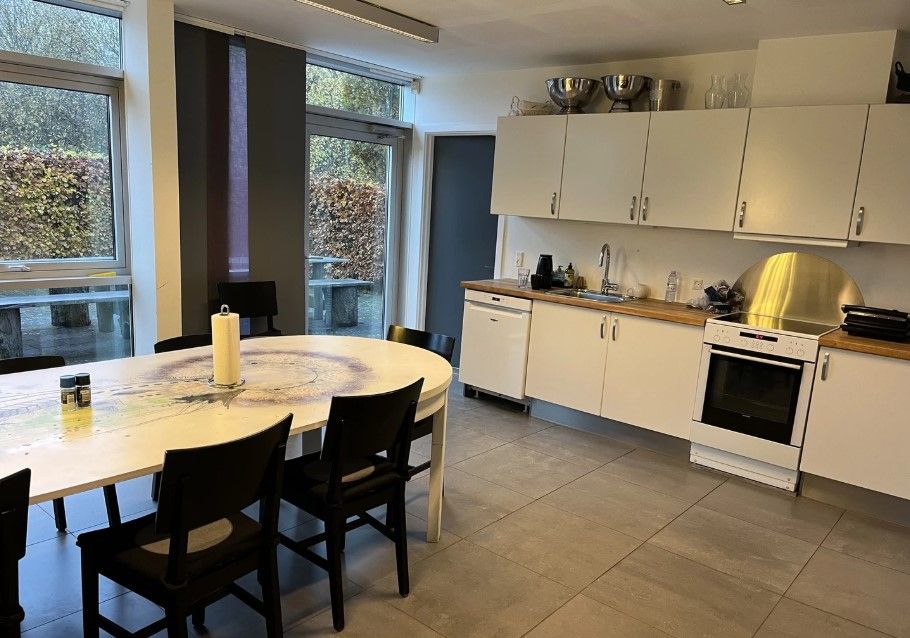 En stor køkken med et rundt spisebord og lyse skabe og hvide vægge