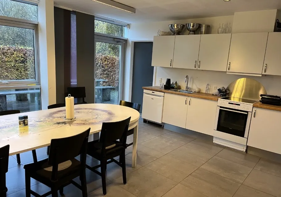 En stor køkken med et rundt spisebord og lyse skabe og hvide vægge