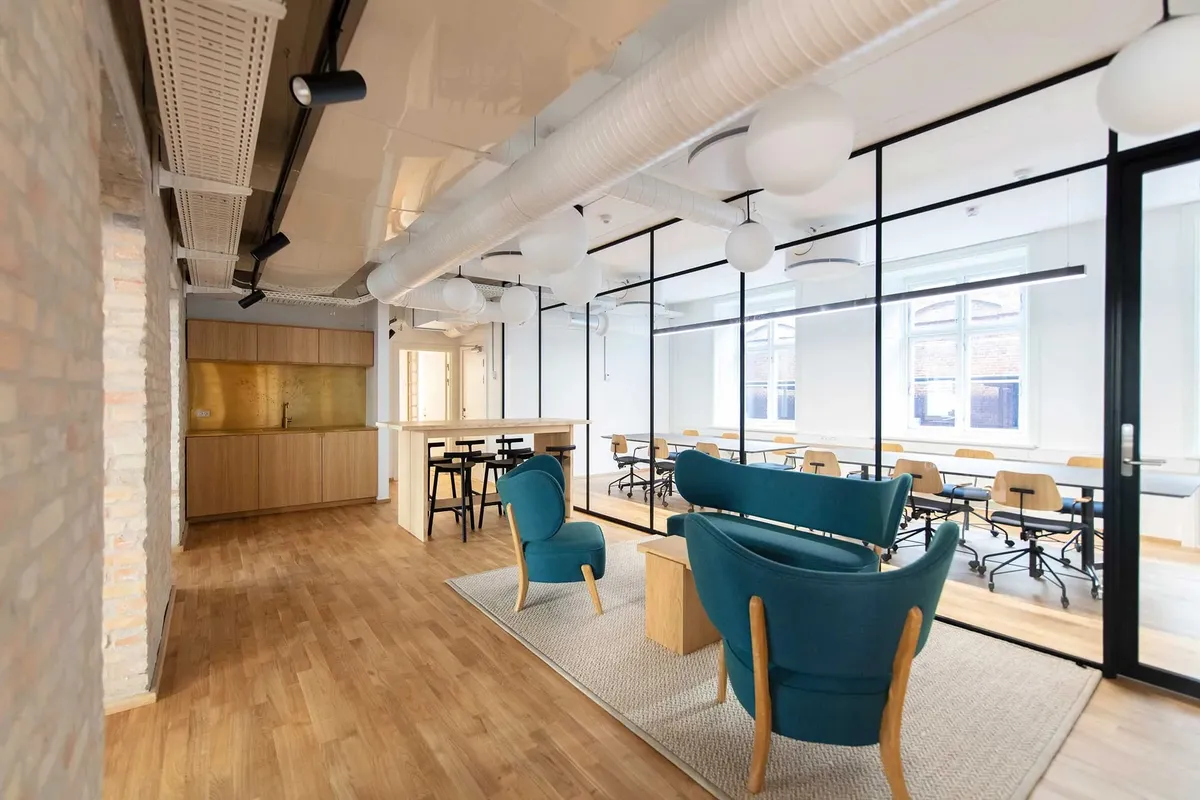 Moderne kontor med højt til loftet og gulv i træ og lyse møbler og stole på gulvtæppe