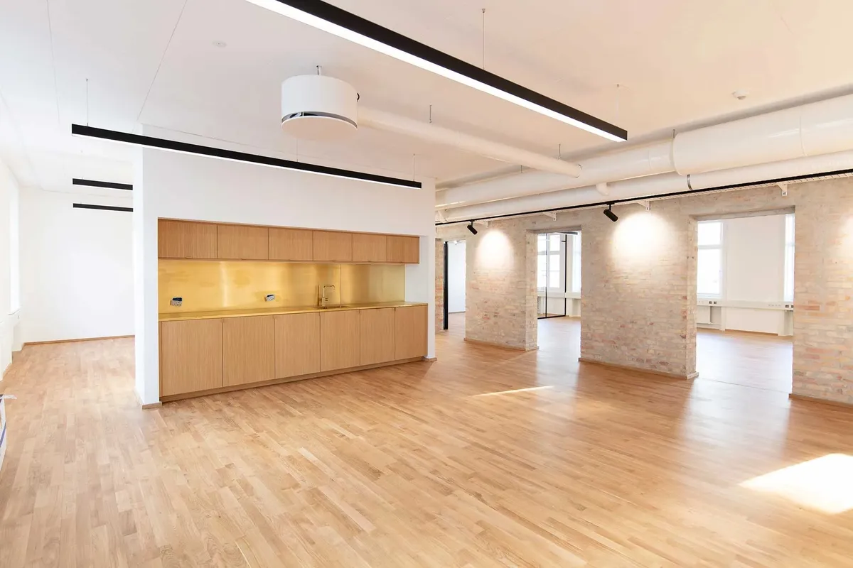 To rum med højloft og massivt træ, lyse gulve og hvide vægge, ingen møbler og ingen mennesker