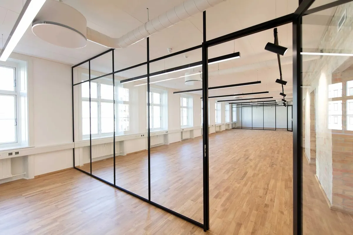 En stor kontorbygning med højt til loftet og glasvægge samt lyse loftslamper og store vinduer i hvidt