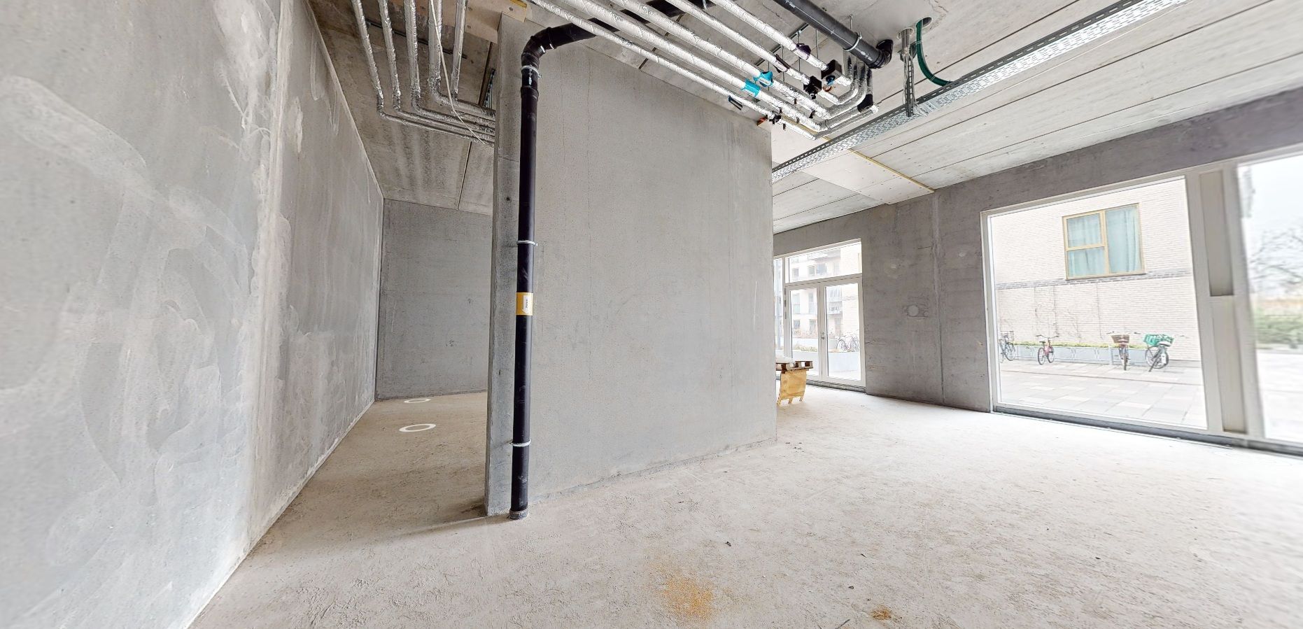 En ny bygning med en hvid gulv og lyse ruder i en ny bydel i Rødovre, med nogle cykler parkeret udenfor