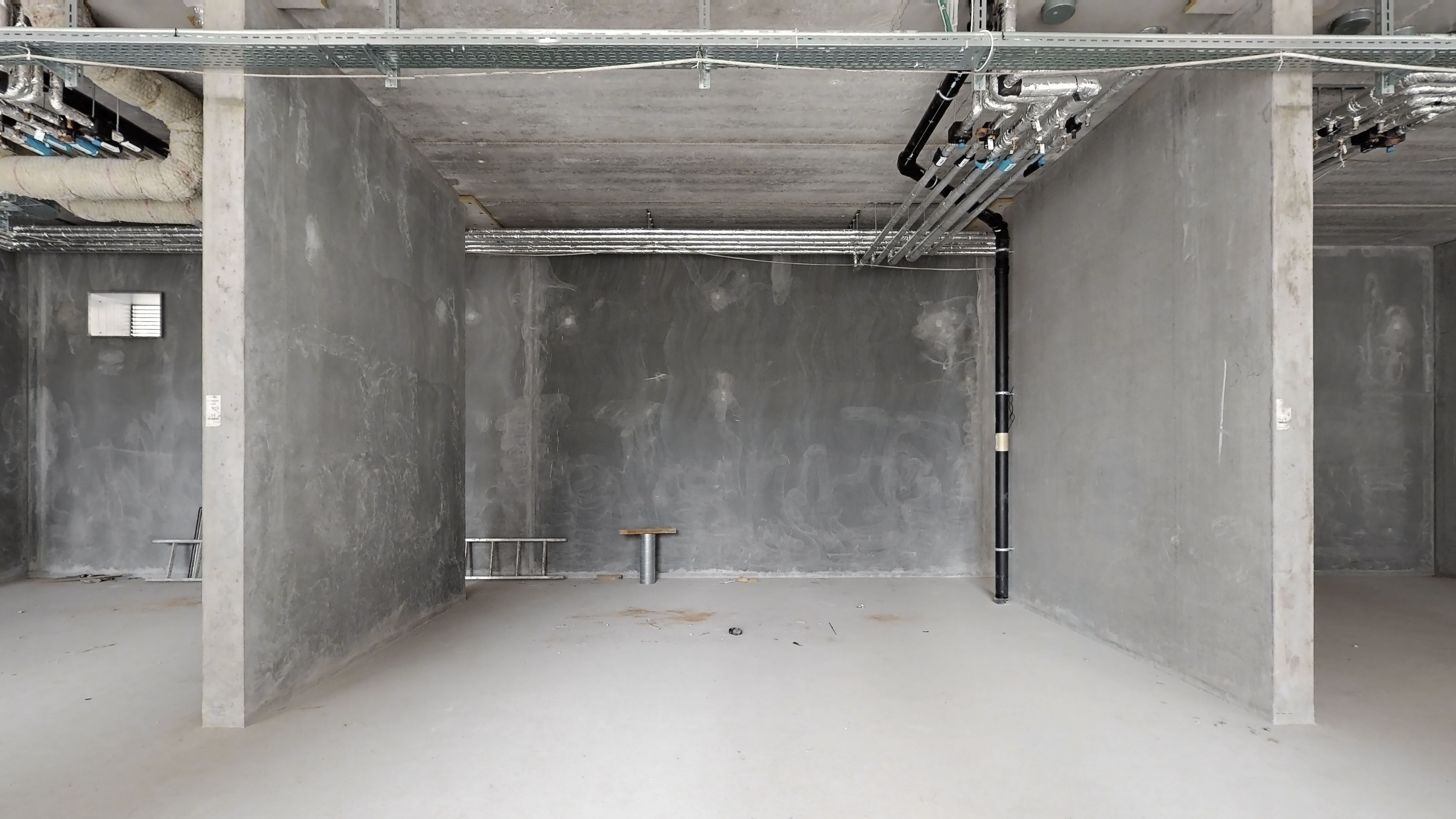 Byggedejlig og ny værkstedslokal i Rødovre, nær stationen, med tomrum, støbejern og rørlægning i loftet.