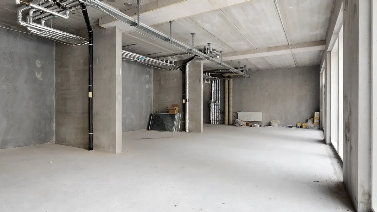 Nybyggeri i centrum af Rødovre med eksponerede betonvægge og rørmærker på loftet