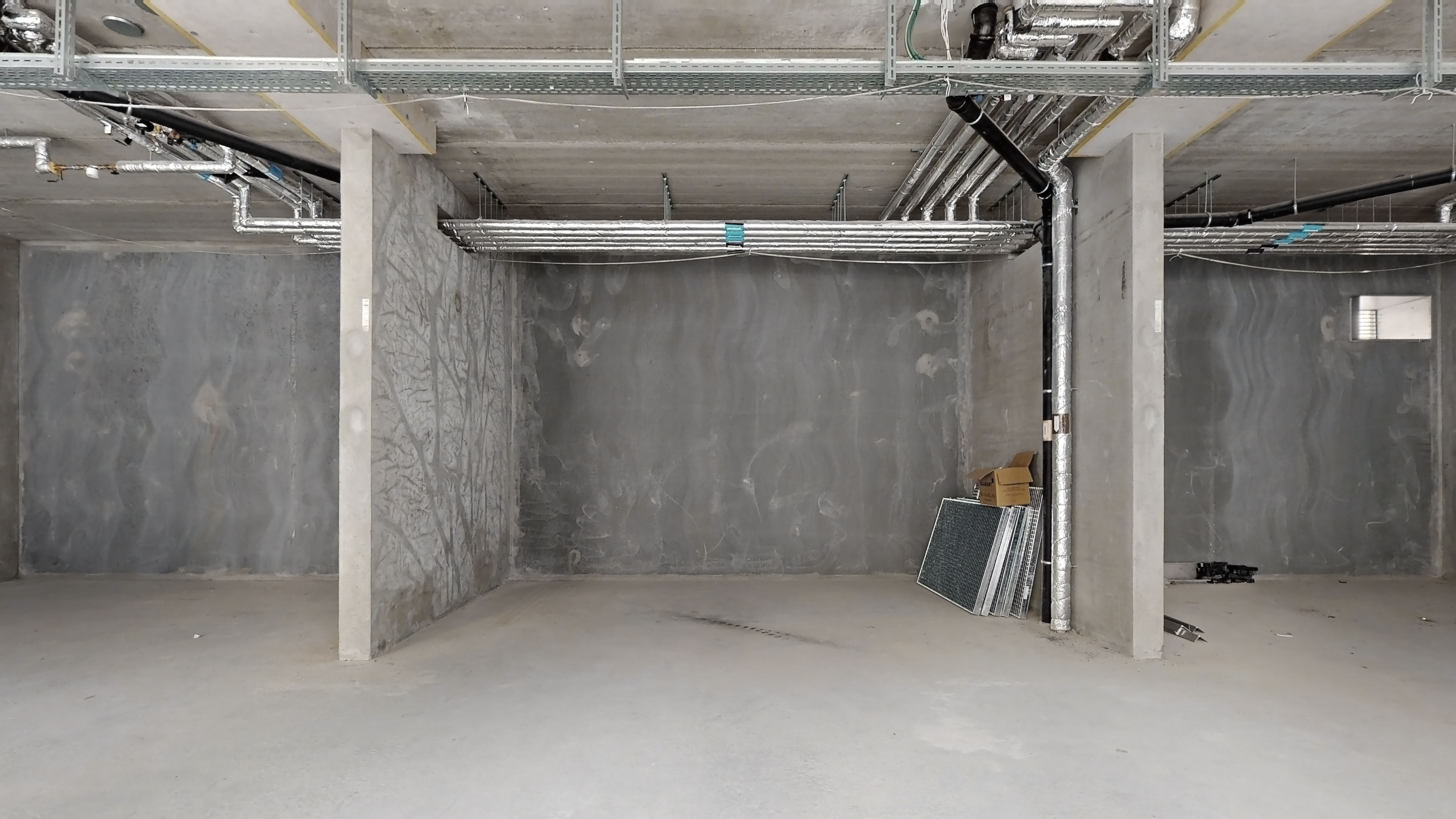 Undergrundsrum med røde og grå vægge, stive metalrammer og røretråde i loftet og på væggene