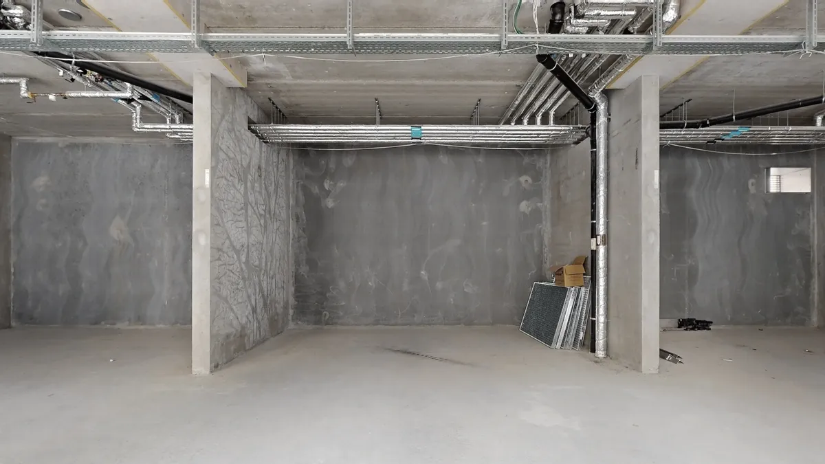 Undergrundsrum med røde og grå vægge, stive metalrammer og røretråde i loftet og på væggene