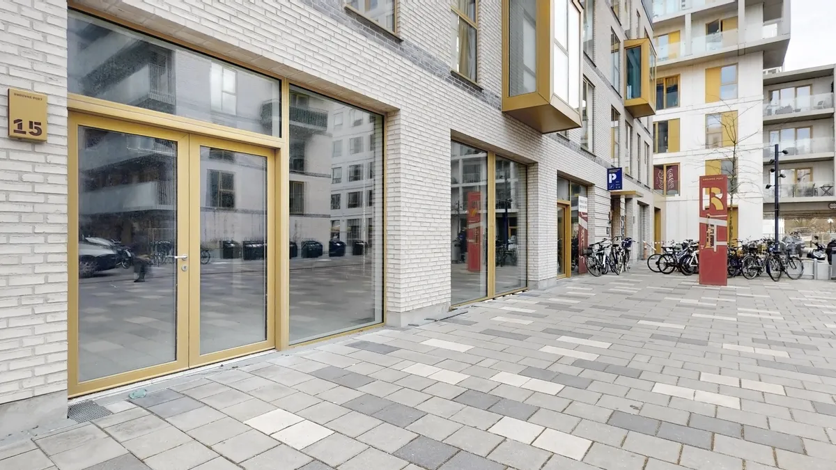 Gammel bydel med moderne facader og glasdøre i Rødovre. En parkeringsplads med flere cykler og bygninger med store vinduer