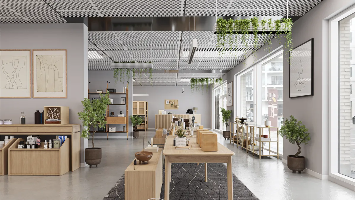 Butik med lyse lofter og møbler af træ, en stor plante i en brun potte, og en række lyse hylder med varer