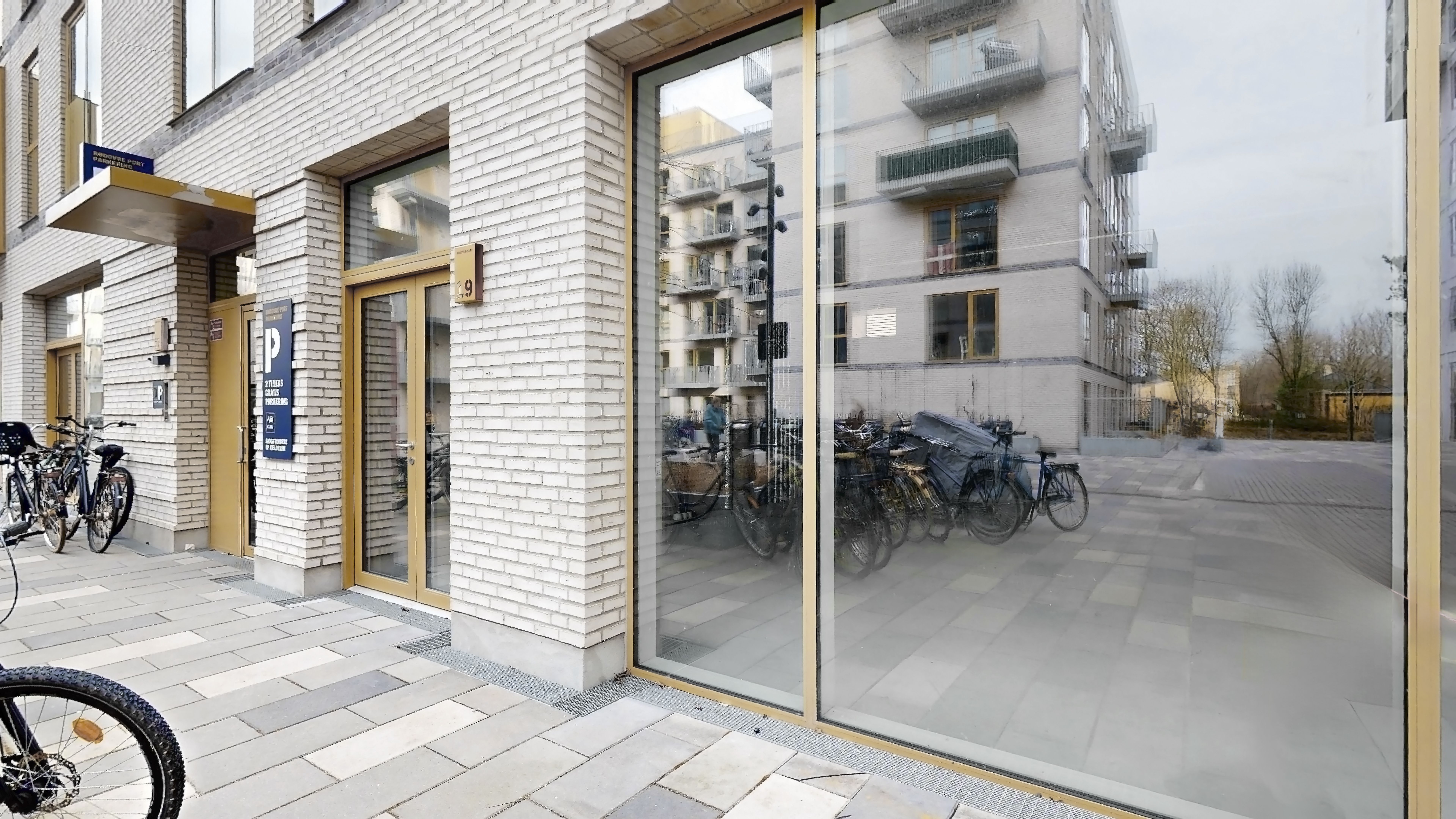 Mange cykler parkeret udenfor bygningen med nummer 2.9 på væggen. Der er en række cykler parkeret på hjørnet af gaden.