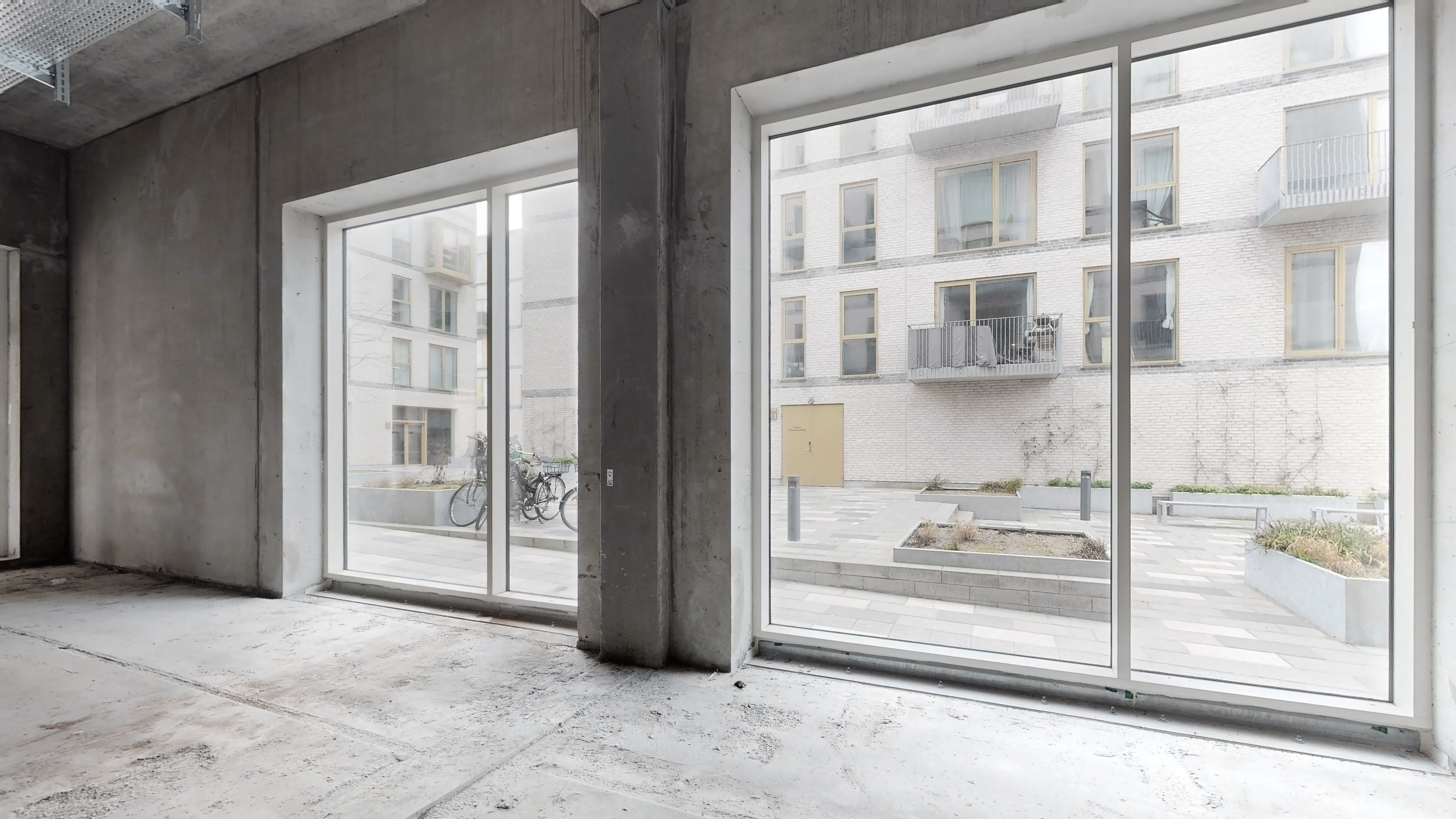 Rødovre bydel med glasruder og vinduer, uden møbler, lysegul trædør og parkeringsbøsser. To cykler udenfor og planter i