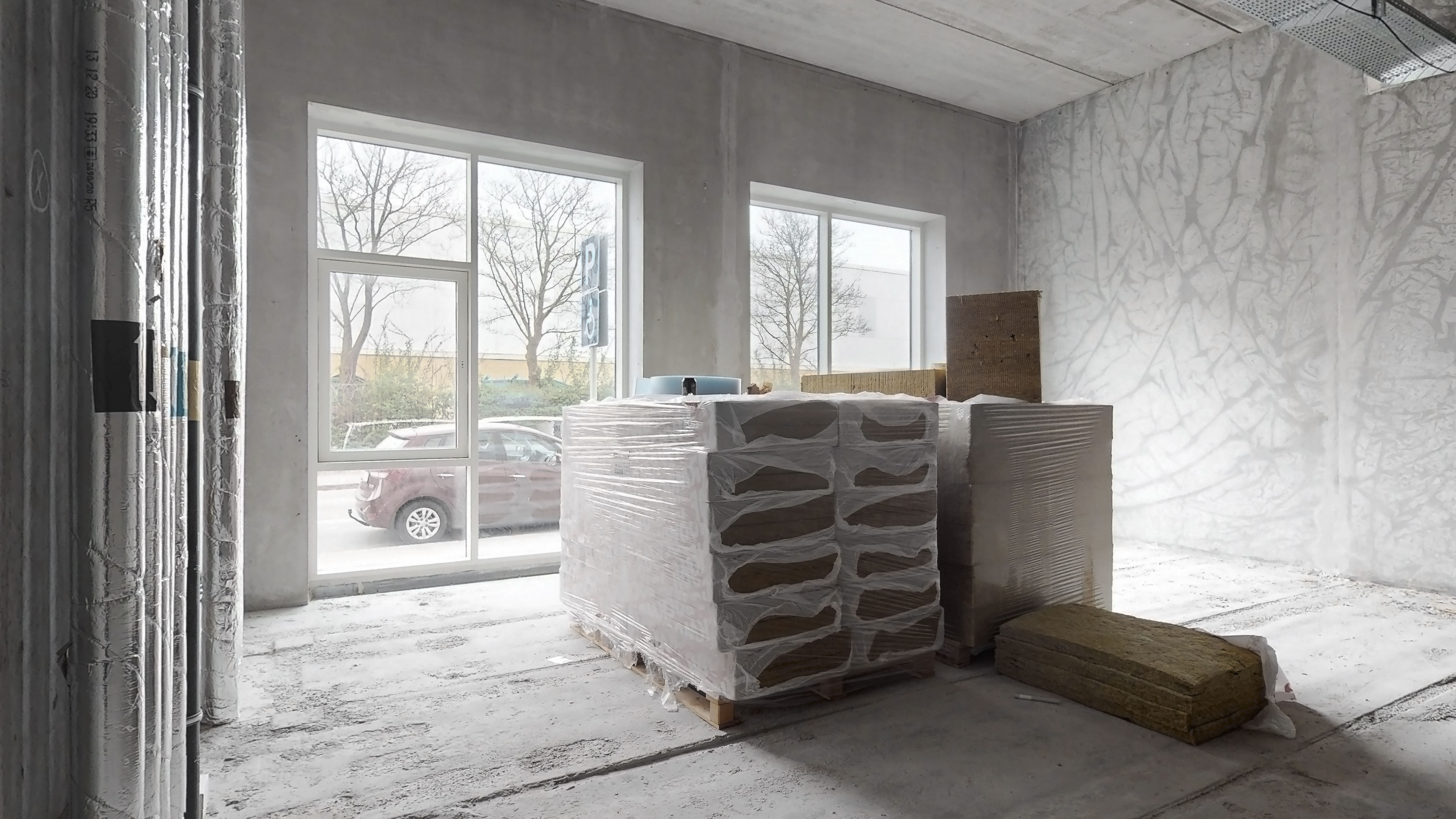 Byggematerialer i en ny butik med vinduer og ingen vægbeklædning. Et glasdør i højre side og to store vinduer med udsigt til