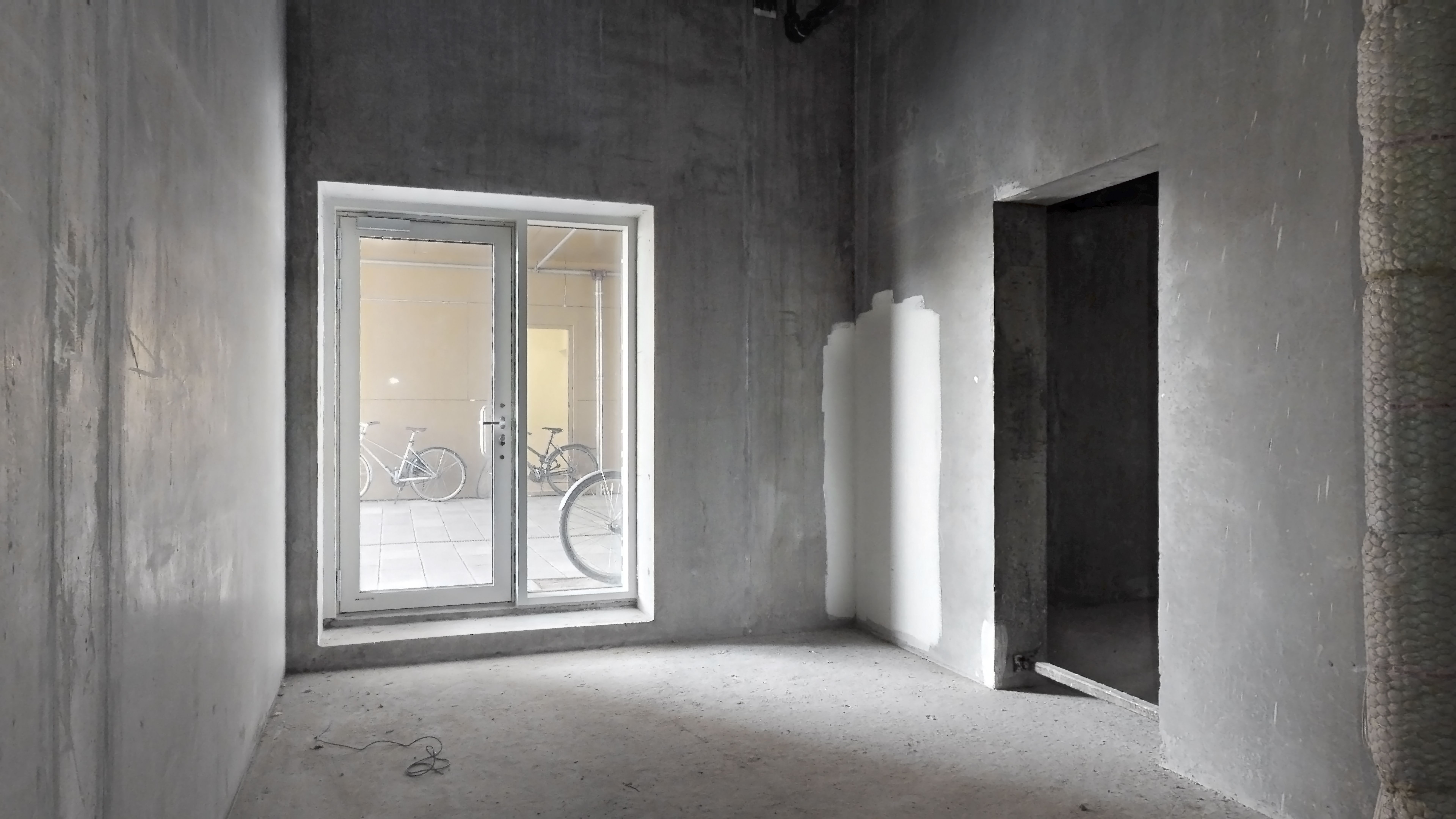 En ny bygning med en dør og et vindue med refleksioner af en cykel og et hus i baggrunden