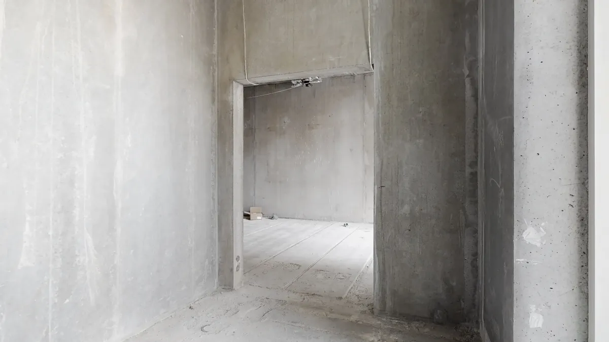 En stor ubenyttet huslejlighed med tørre vægge og gulv samt åbne døre og en lille kasse på gulvet i baggrunden