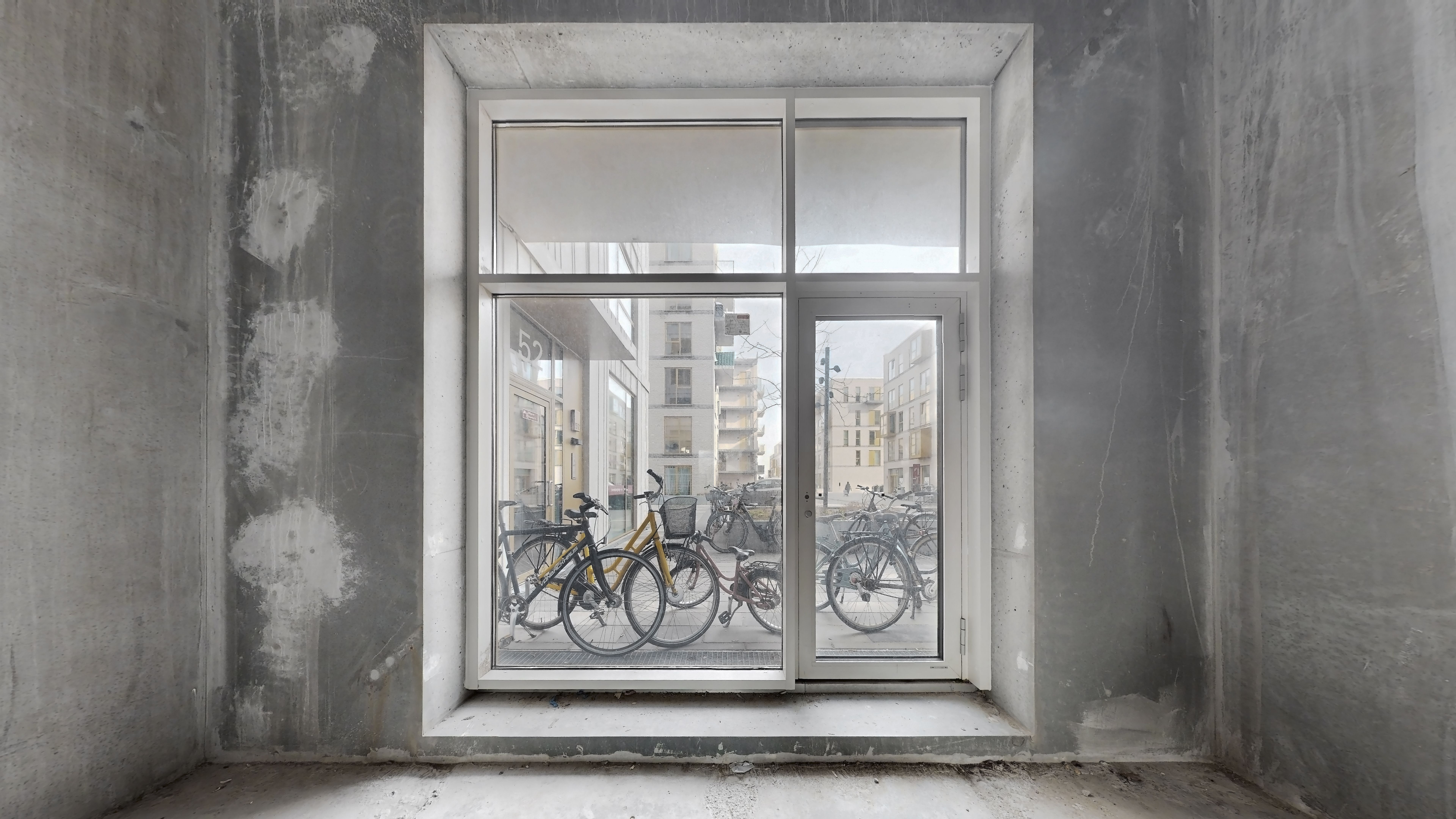 Vindue i et byggeloft med udsigt til gaden og cykler parkeret udenfor i byen