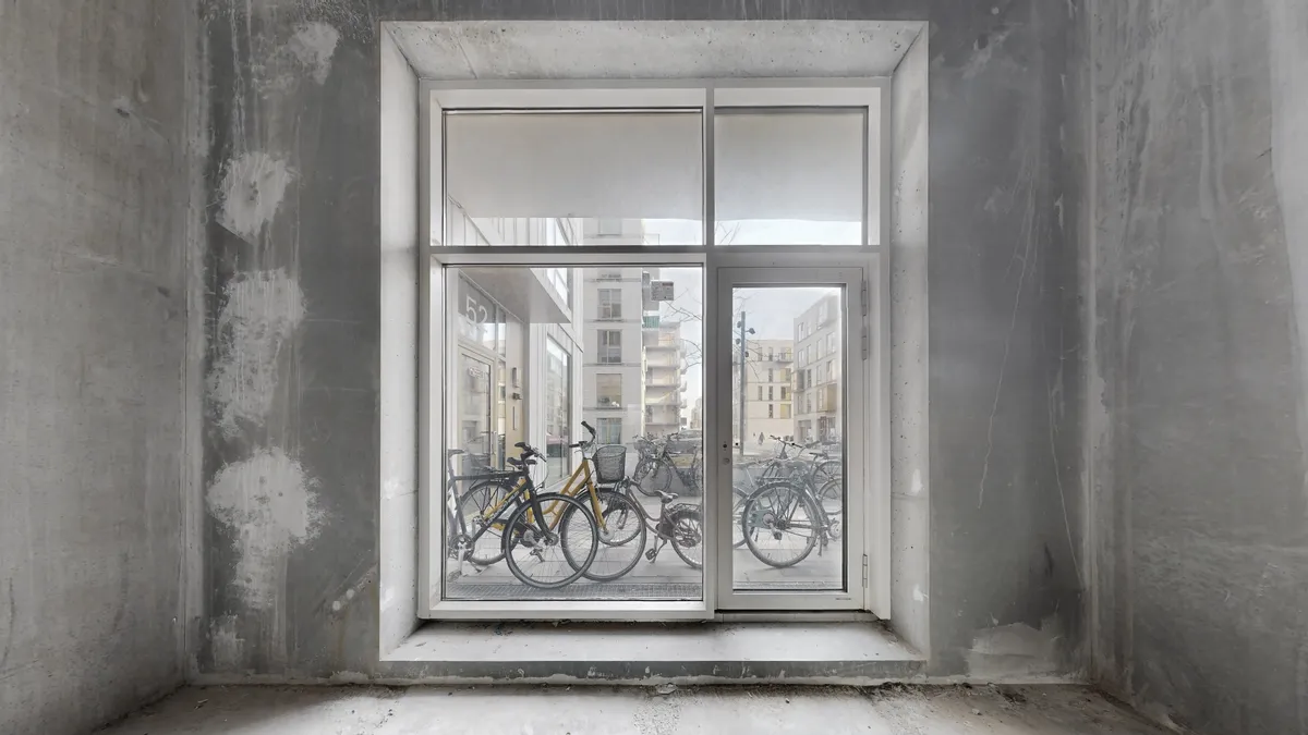 Vindue i et byggeloft med udsigt til gaden og cykler parkeret udenfor i byen