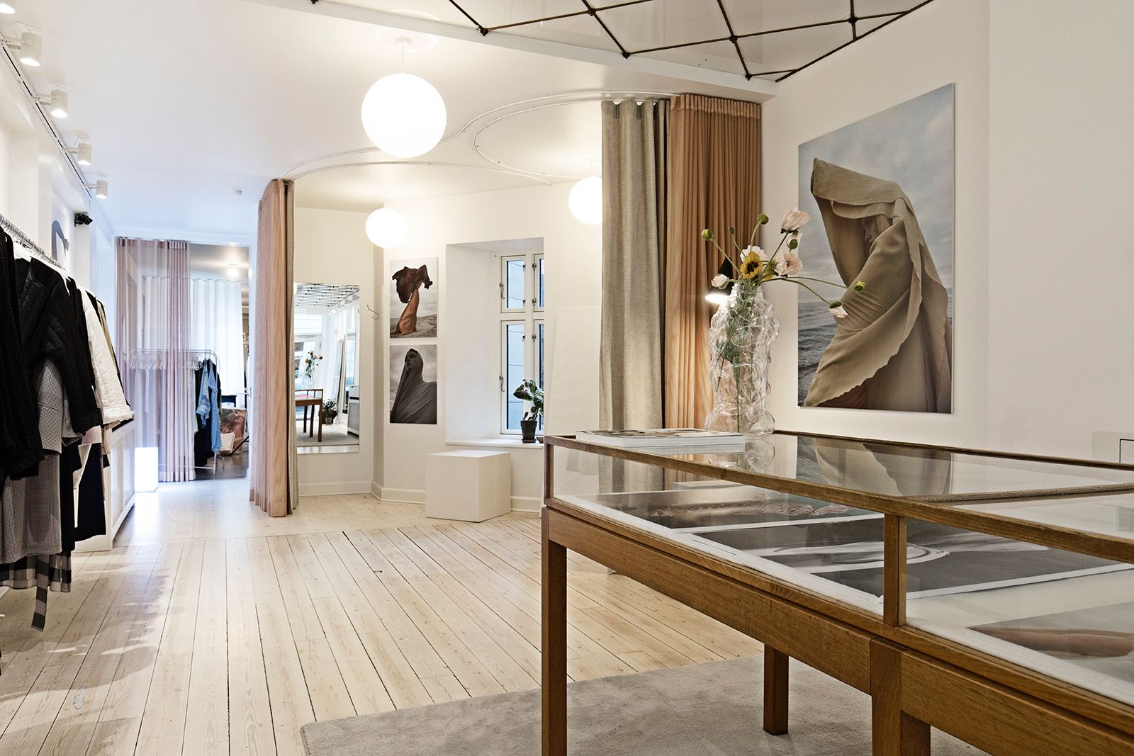 En klædeskab med mange hængehylder og flere billeder på væggen med lyse lysekopper og et spejl med en blomst i en vase og et