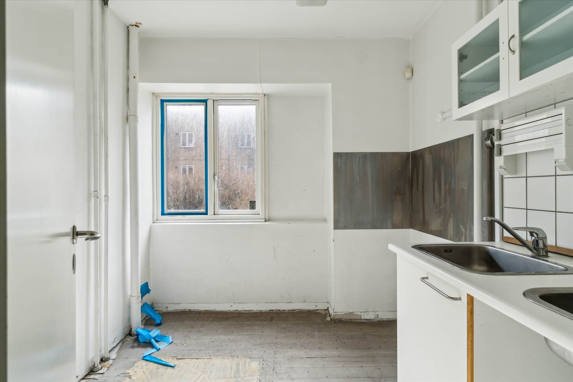 Ledig køkken med åbent vindue og ny gulvbelægning samt to nye vandhaner og en enkelt hængende vask