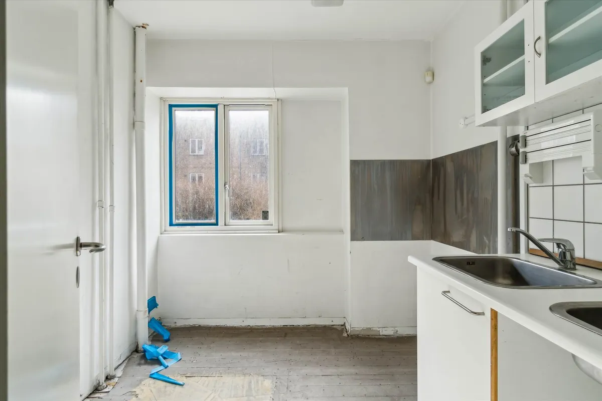 Ledig køkken med åbent vindue og ny gulvbelægning samt to nye vandhaner og en enkelt hængende vask