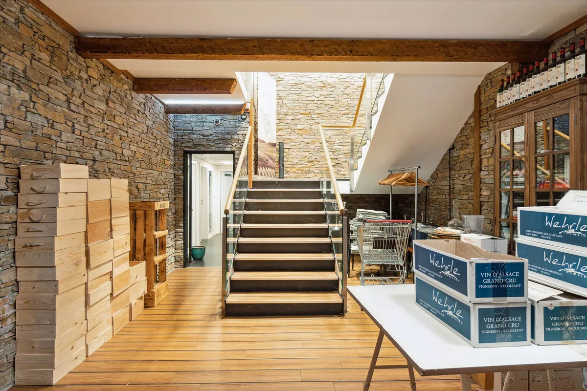 Lager med vinkasser og træbjælker samt trappe og glasgulv i baggrunden