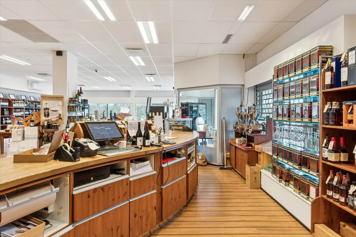 En butik med et moderne design, flere stolpehyller og et sælgerpult med computer, papirkurv og skraber