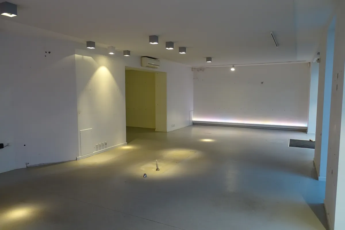 En stor, lys og tom lokale med hvide vægge og gulv samt lysepunkter og en dør i væggen