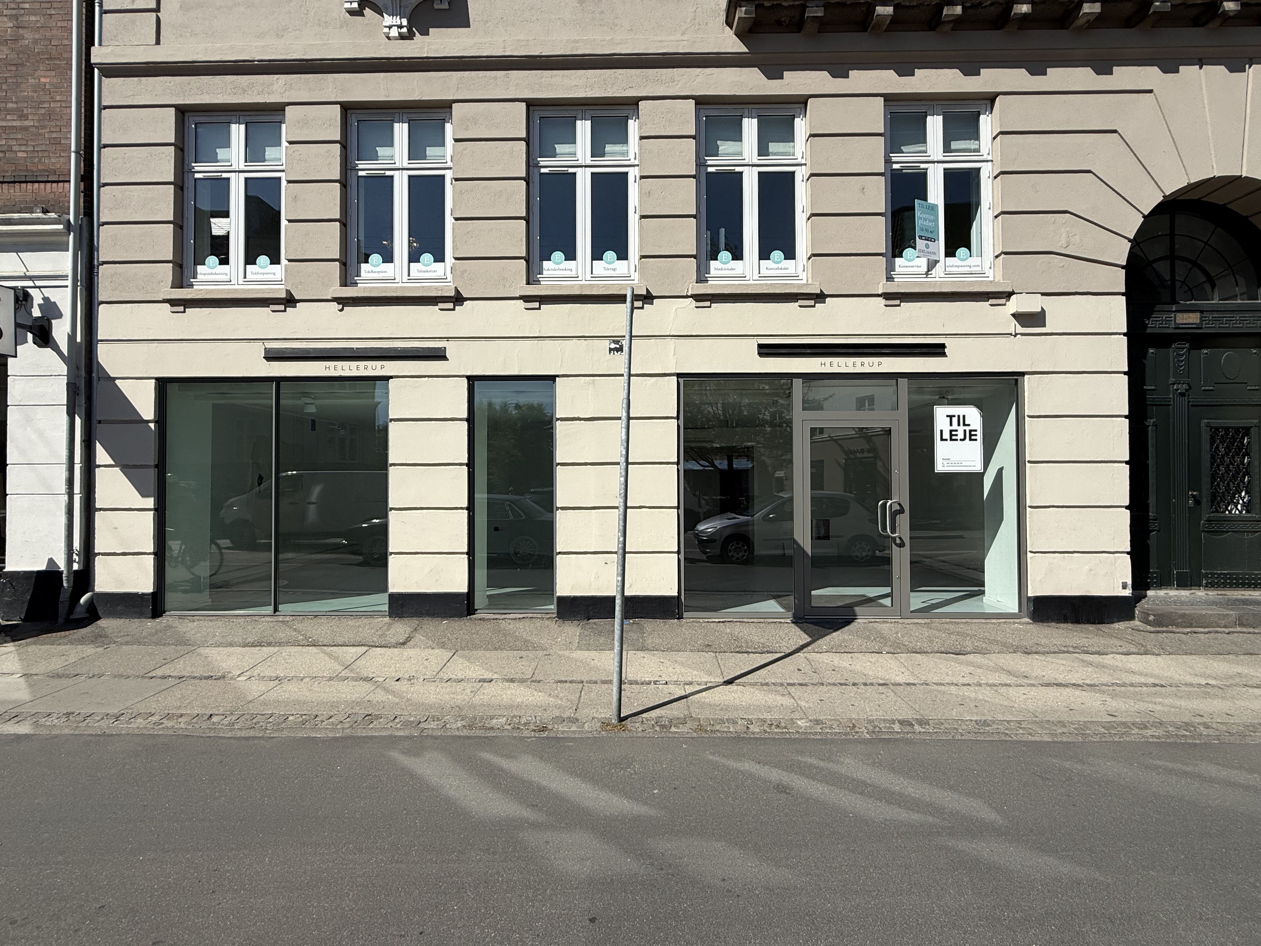 Butikslokaler til leje i Hellerup. Det står skrevet på døren, og der er flere biler parkeret foran.