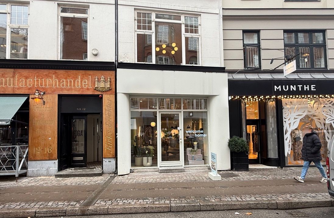 Butiksgade med butikker, herunder Munthe, og en forbipasserende i jeans og sneakers.