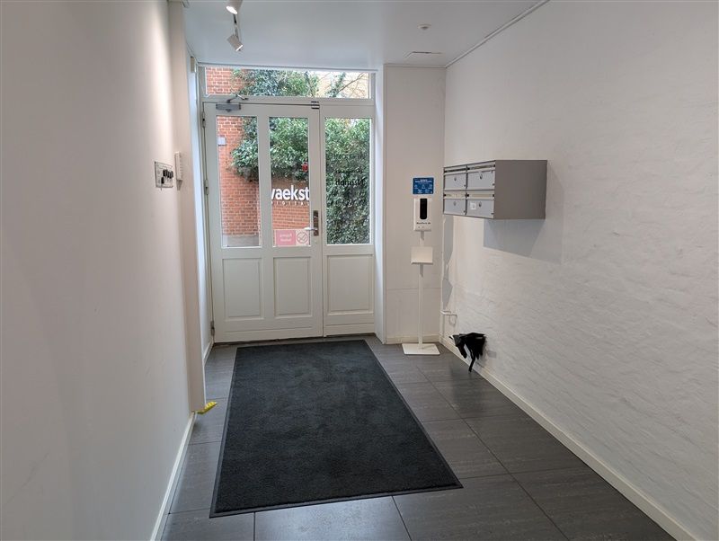 Kontor med hvide vægge og en stor dør med teksten vaekst. Der er en høj kvalitetsgulv og et sømløst integreret søgefelt med