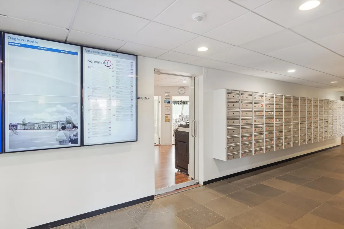 Kontor med moderne design, gulv, møbler, skriveborde, postkasser og digitale displayer med information