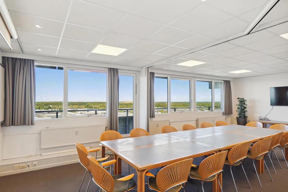 Kontor med moderne møbler og vinduer med udsigt til byen. Store borde og sæder til møder og begivenheder