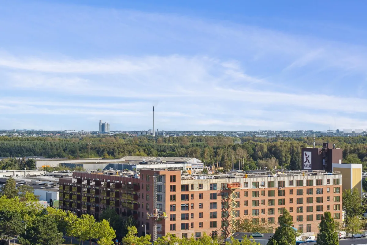 Kontorbyggeri i Glostrup med tårn i baggrunden og mange vinduer og facader i røde mursten