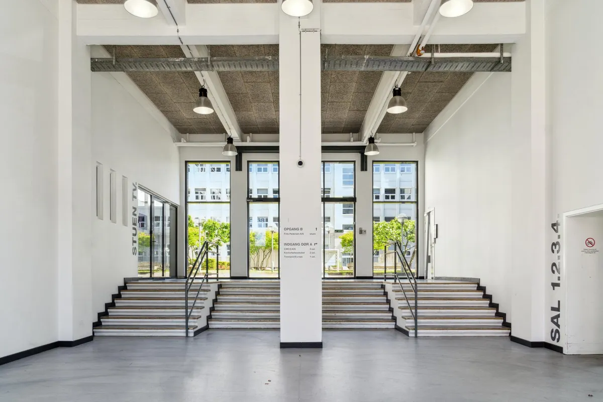Et indgangsområde til et kontorlokal med hvide vægge, højloft og fire indgange til opgang B og opgang D.