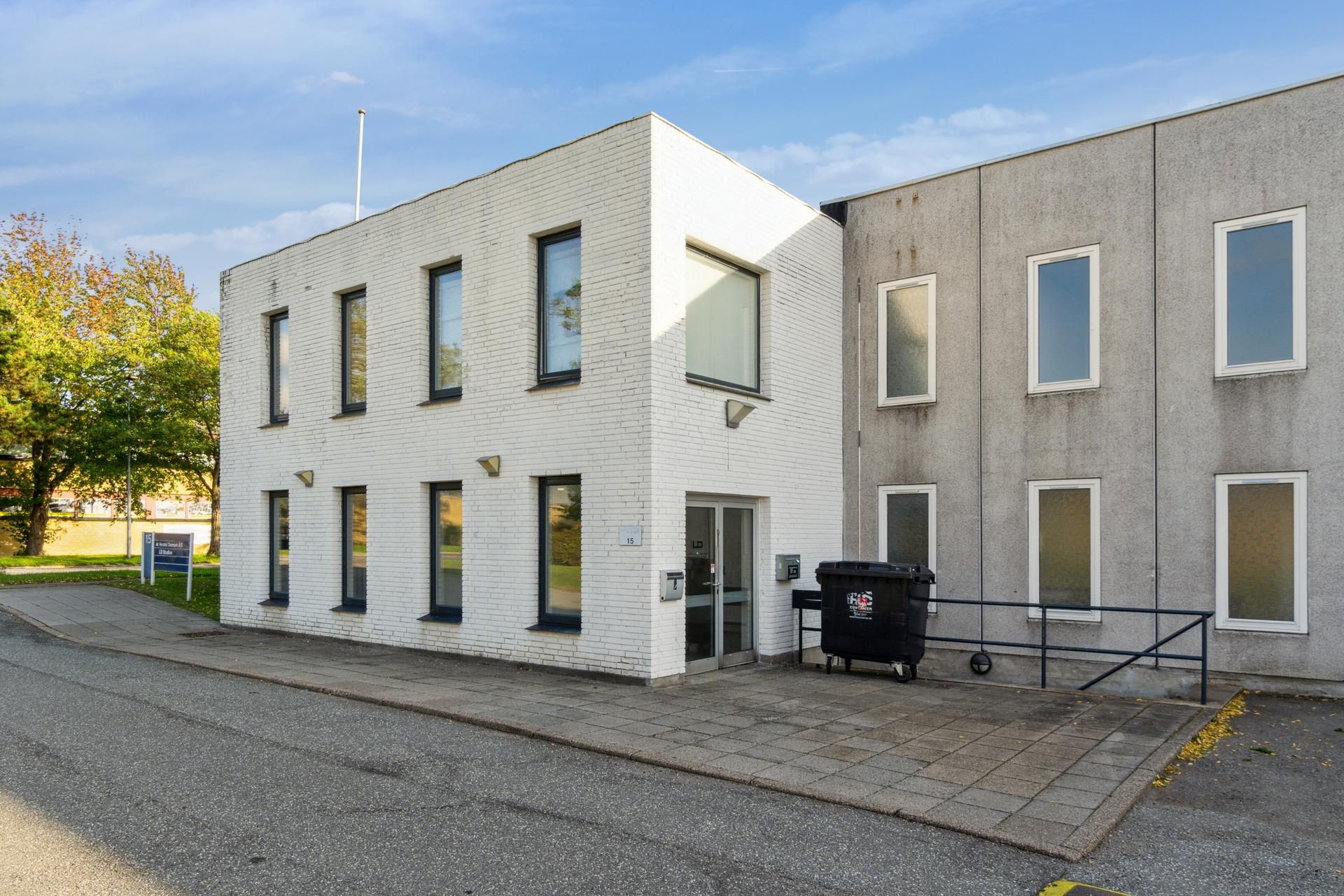 Et hvidt og enkelt bygning med flere vinduer og døre samt en skraldespand og håndtag ved siden af pavillonen