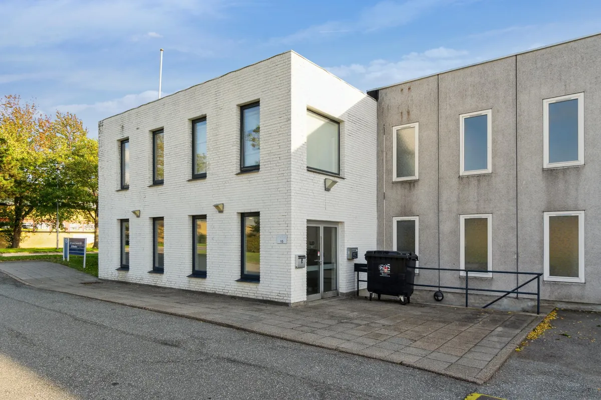 Et hvidt og enkelt bygning med flere vinduer og døre samt en skraldespand og håndtag ved siden af pavillonen