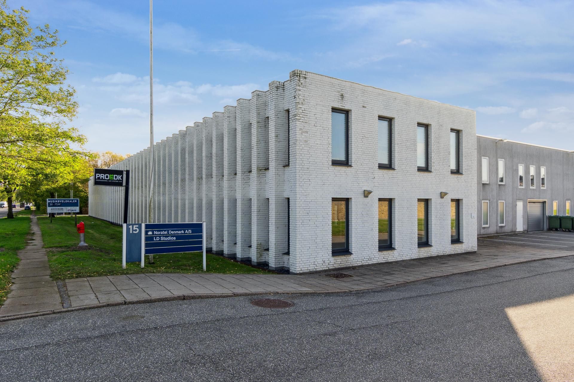 En hvid erhvervsejendom med nummeret 15 og skiltet NORATEL DENMARK A/S LD Studios