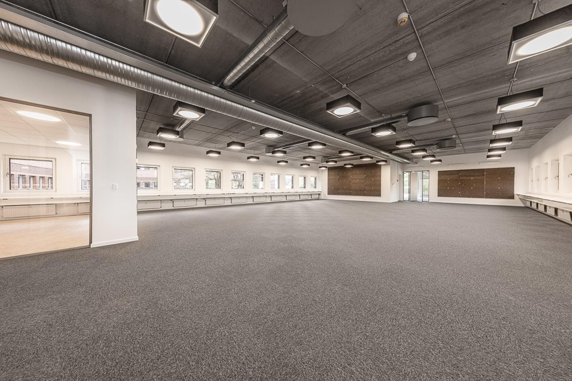 En stor og møbleret konferencesal med lyskugler og hvide vægge og lofter