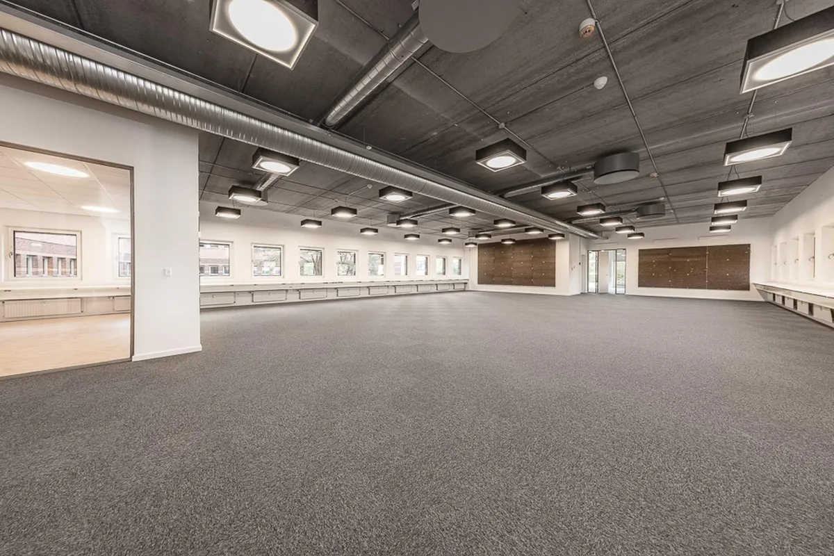 En stor og møbleret konferencesal med lyskugler og hvide vægge og lofter