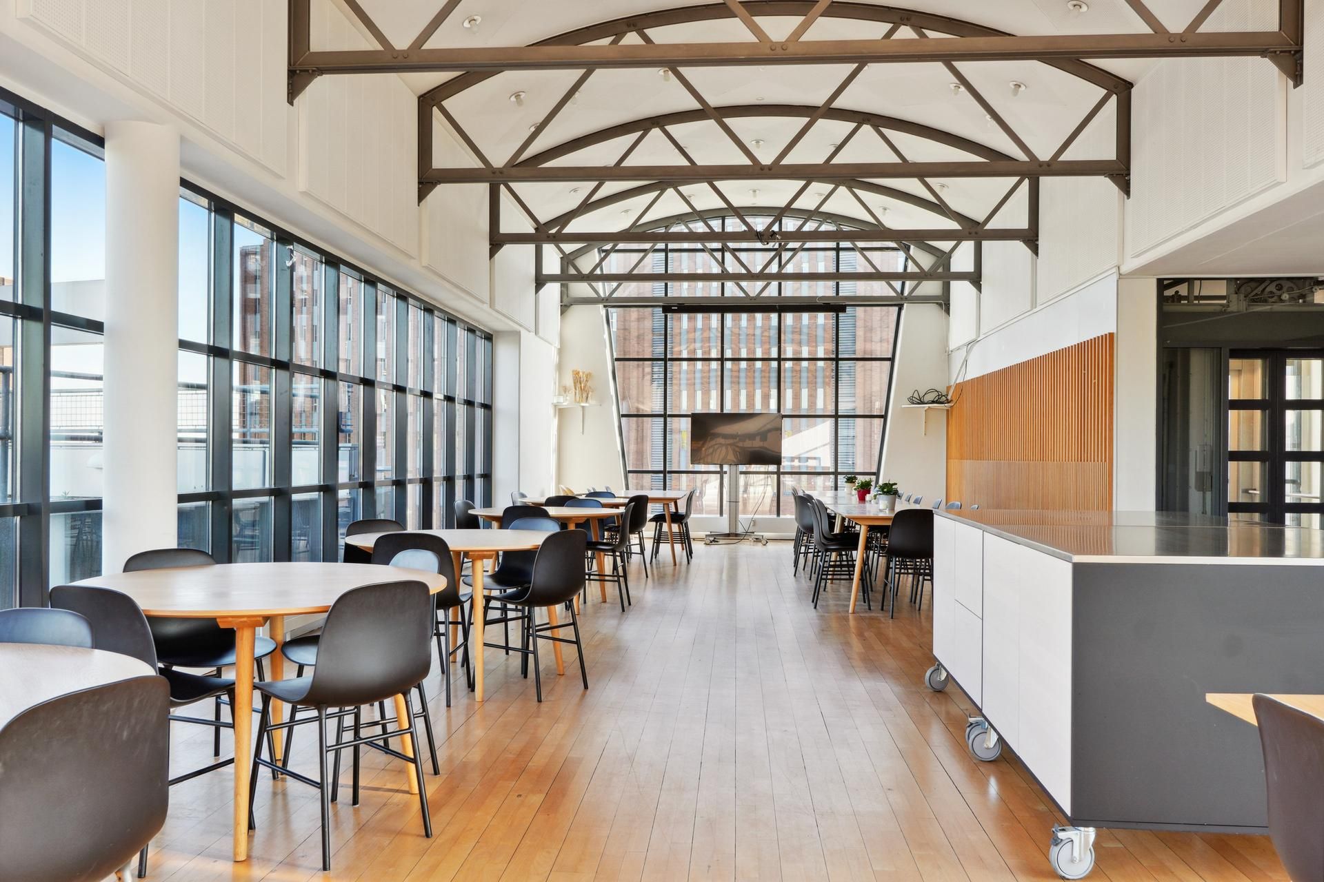 Kontorfællesskab med moderne møbler og lyse vinduer i en bygning med højt loft og åbne områder