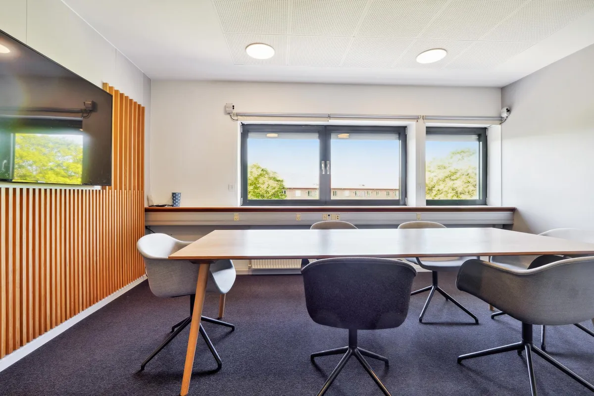 Kontor med møbel og tekstiler i lyse farver og lysevinduer i en forretningsbygning