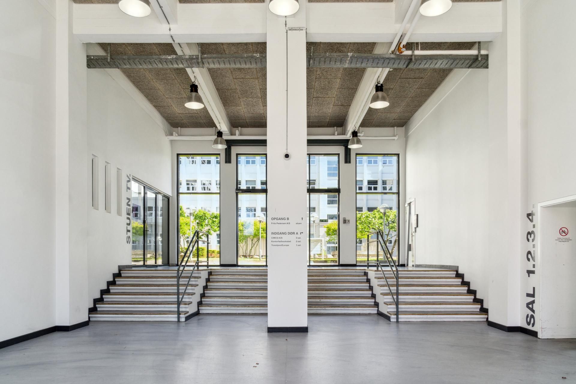 Kontorfællesskab med store glasruder og mønterne Stuen, Opgang B og Indgång Dør A. Hvidt vægdekoration med håndtag til