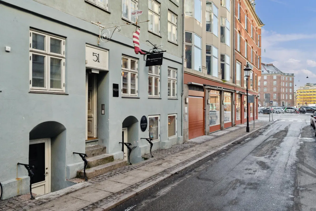 Butikslejemål i København med moderne interiør og boutiqueindretning, vinduer med søjler og stolpelampe på fortovet