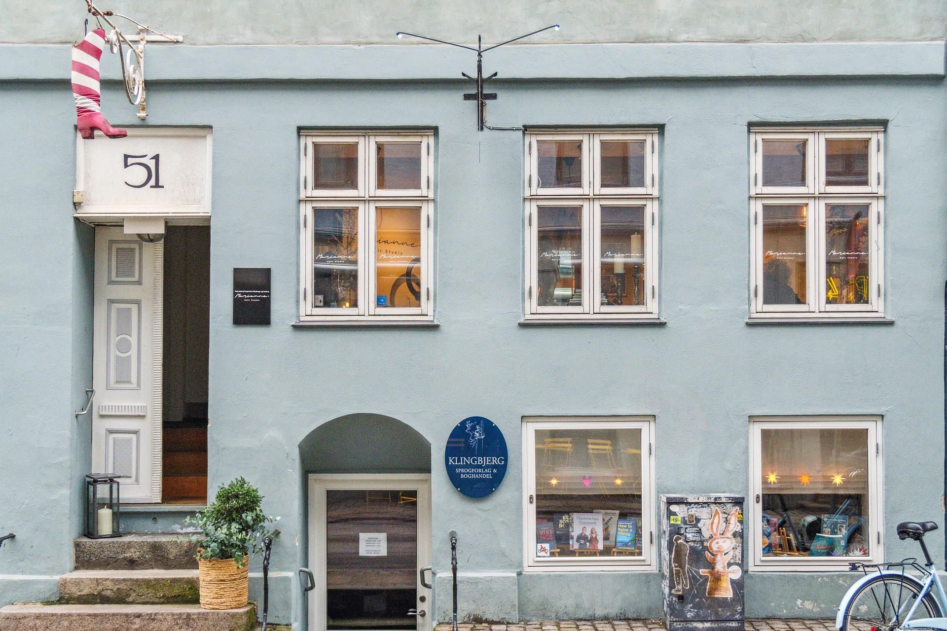 Butikslejemål med numre 51 og 60 på Sankt Peders Stræde med en dør og et vindue med teksten Klingbjerg og boghandel