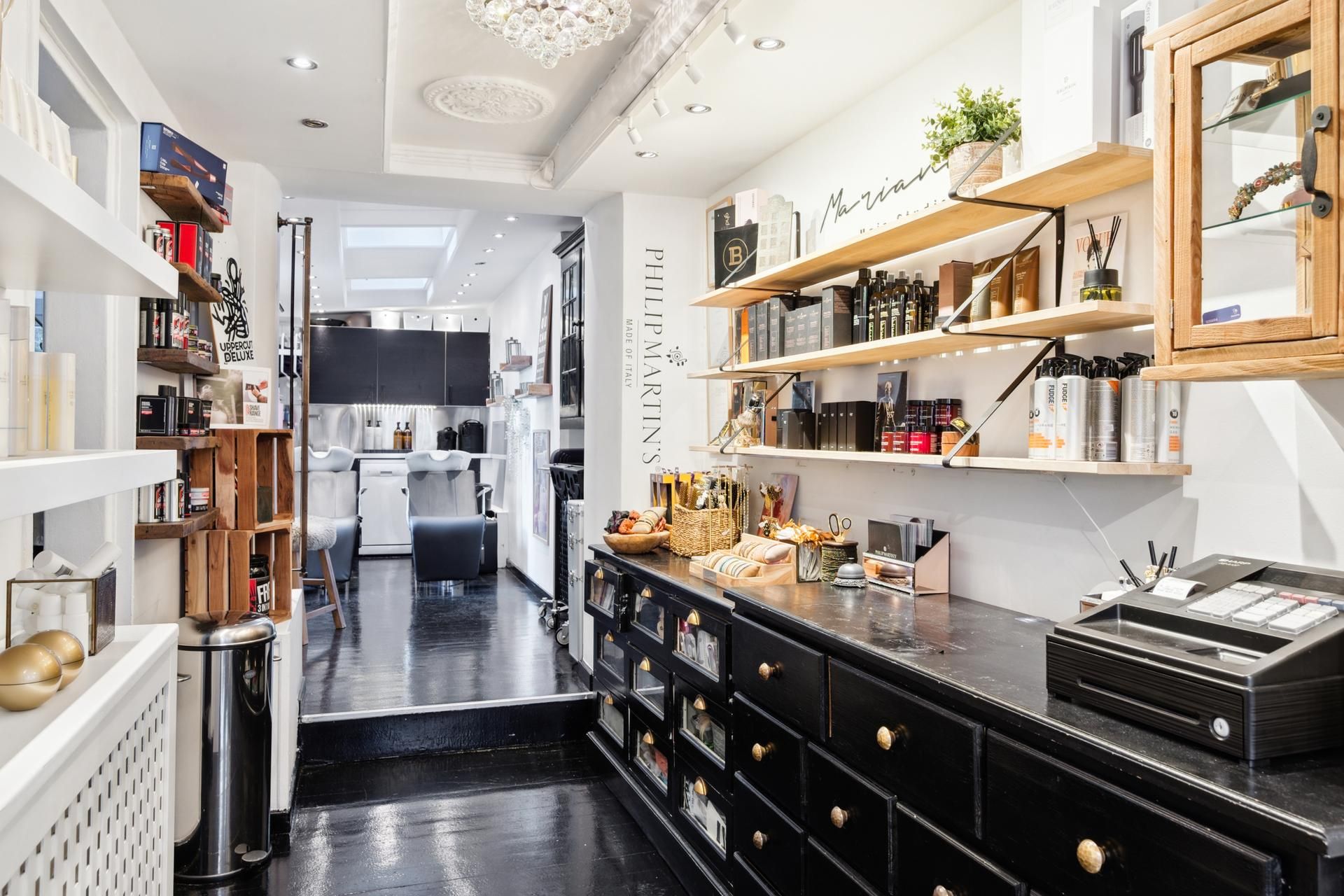 En butik med lyse vægge og møbler og hylder med sort og brun farve, der er fyldt med diverse produkter og prydet med