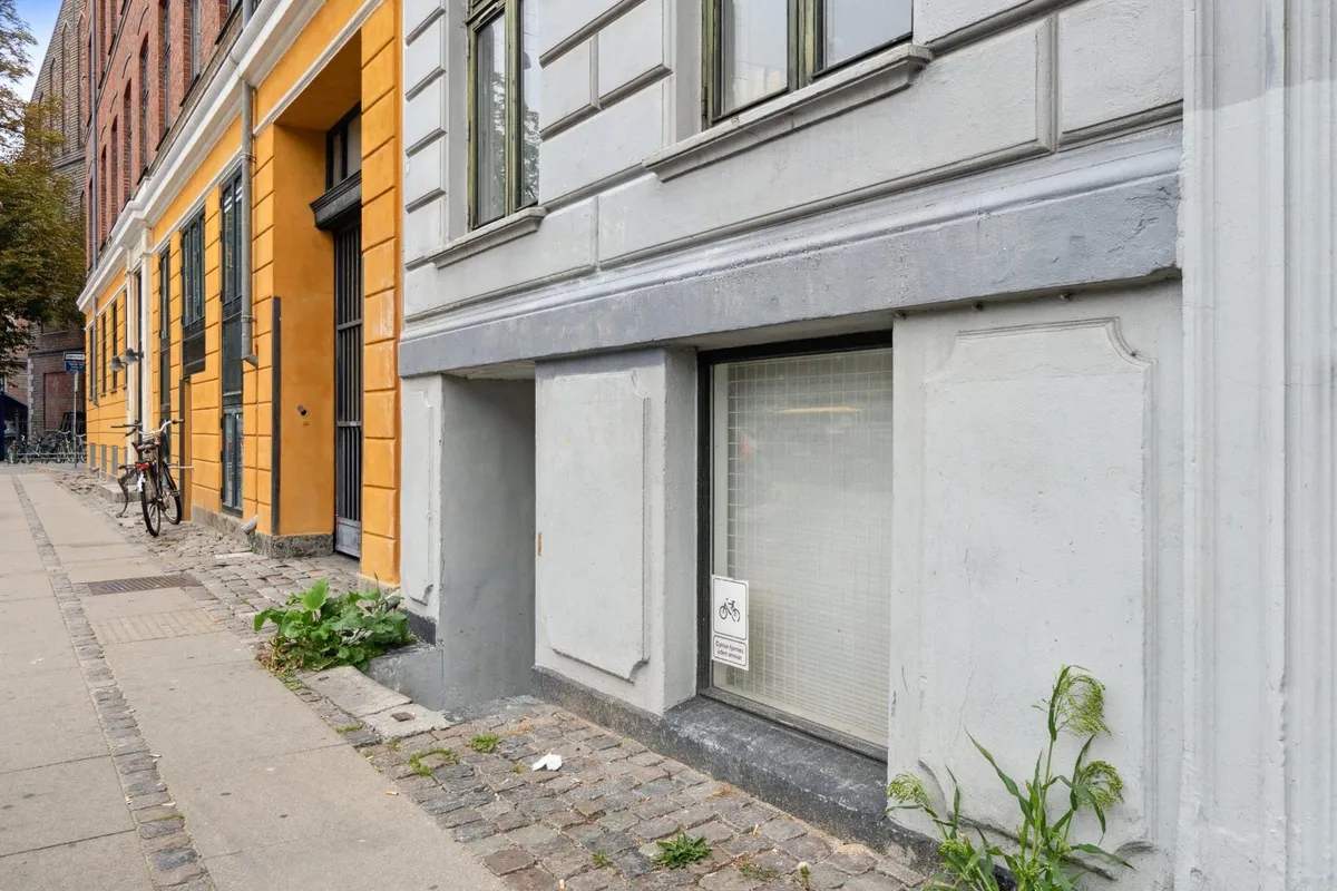 En nedslidt bygning med en gammel gule facade og flere vinduerne samt en cykelparkeringsskilt