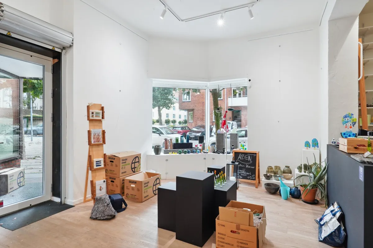 Butik med glasdøre og vinduer, fuld af smukke genstande og planter, og flere kasser med etiketter