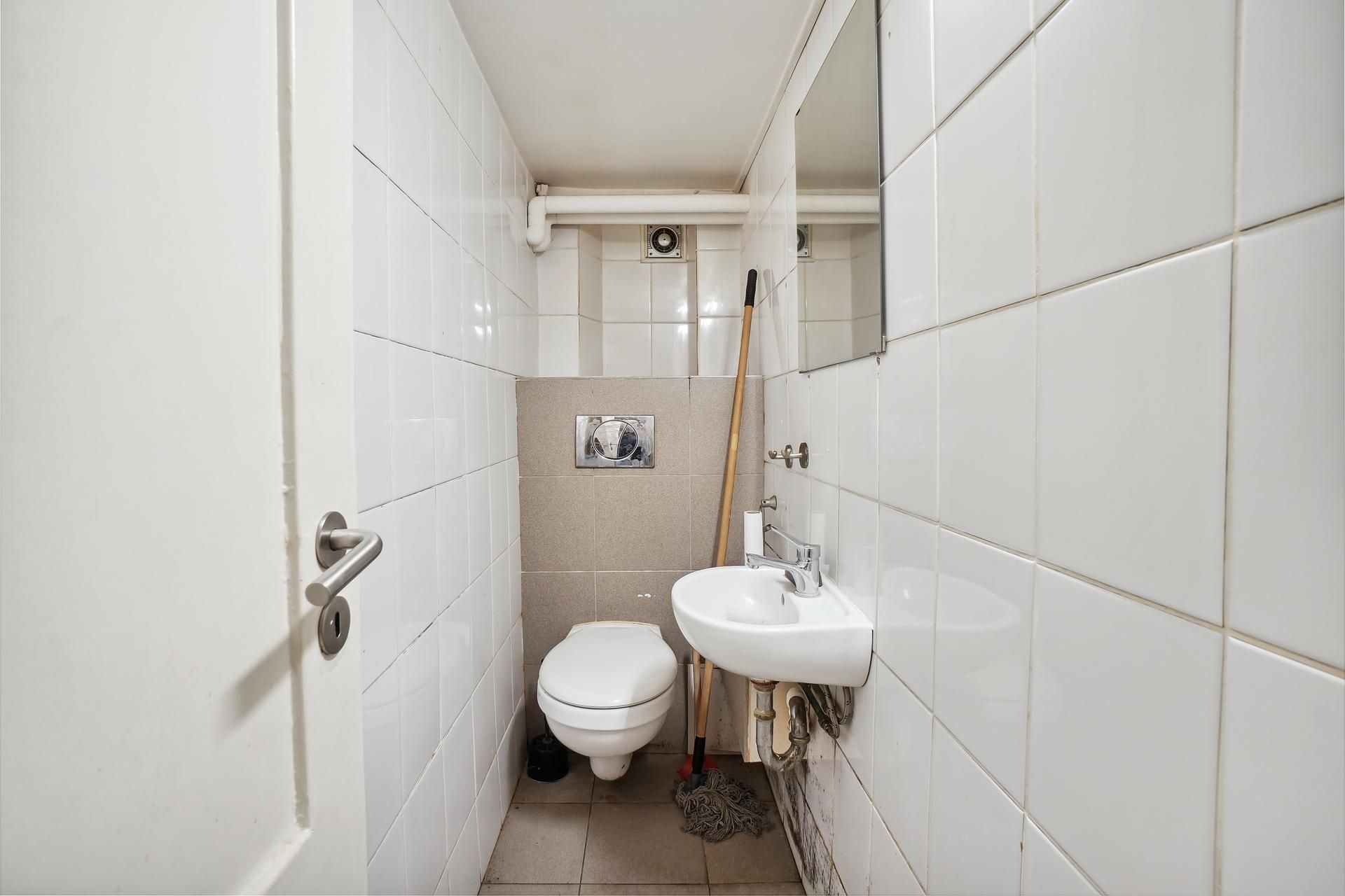 Rent og nyt toilet med hvidt toilet, hvidt spejl og en børste samt en skål med sæbe på håndvask.