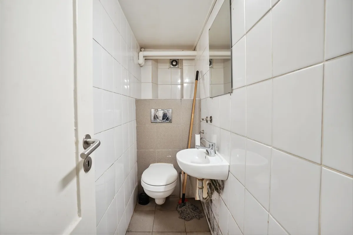 Rent og nyt toilet med hvidt toilet, hvidt spejl og en børste samt en skål med sæbe på håndvask.